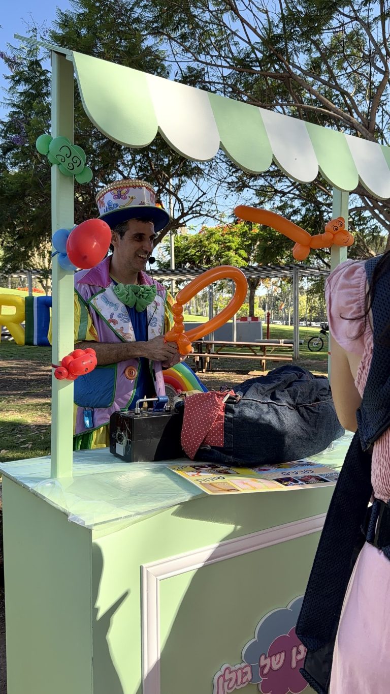 אמן בלונים יוצר יצירות בלונים בעמדה ירוקה באירוע גאווה