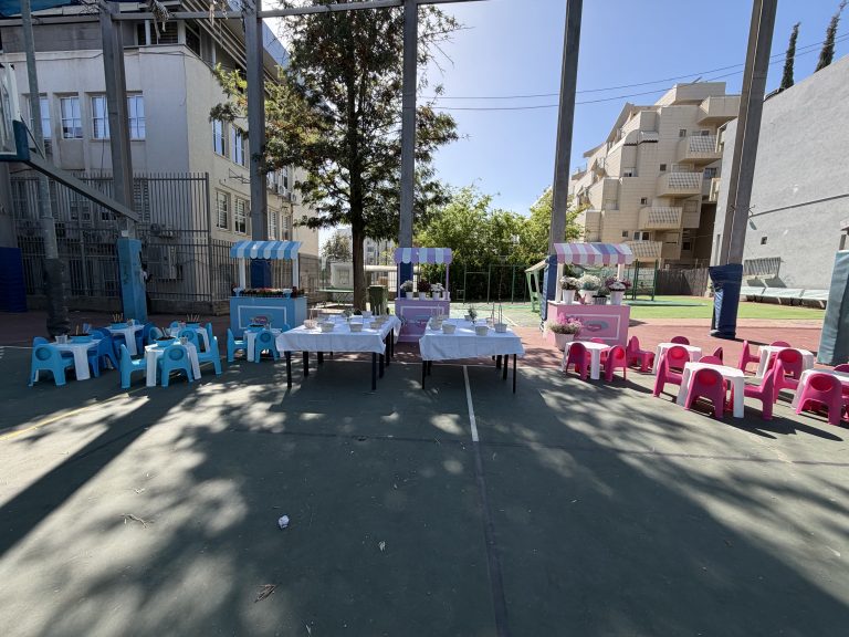 שולחנות וכיסאות מסודרים בחצר בית הספר לאירוע שבועות