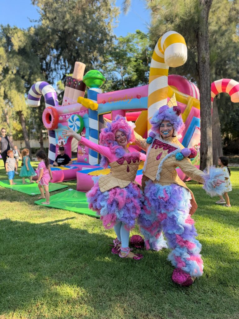 מופע אמנים בתלבושות ממתקים ליד מתקן מתנפח בעיצוב סוכריות