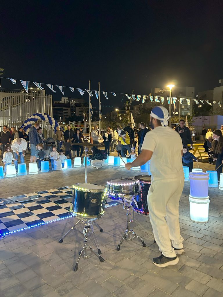 מופע תופים לילי בלבן עם קישוטי דגלי ישראל באירוע הפנינג עצמאות