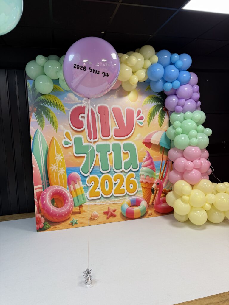 קיר צילום ממותג "עוף גוזל 2026" בעיצוב חוף קיץ, עם עמוד בלוני פסטל